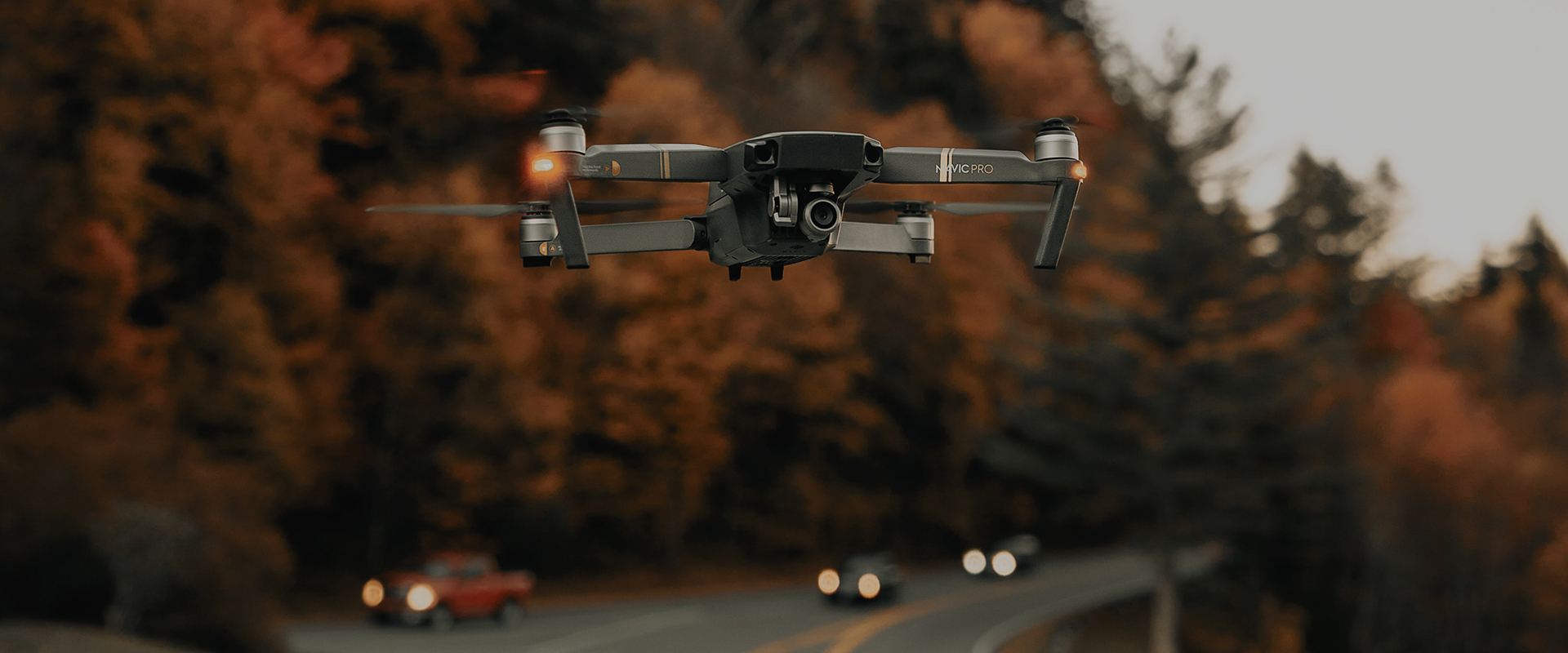Drone flying over road with cars, by forest