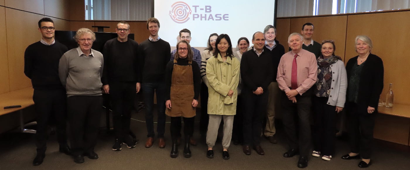 T-B Phase team in from of slide projector displaying T-B Pahe logo